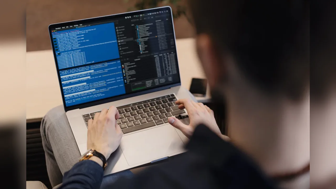 A person typing code on a laptop, seen over their shoulder