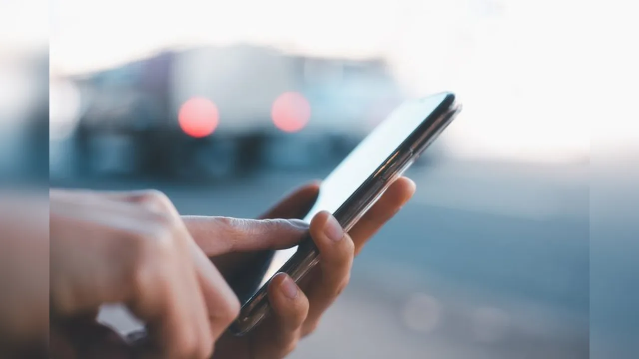 Hands holding a smartphone outdoors, thumb on the screen