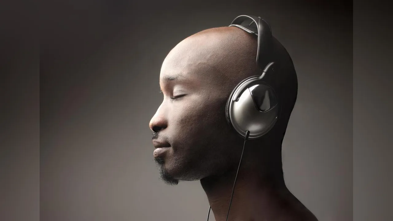 A man wearing large headphones with his eyes closed, listening to music